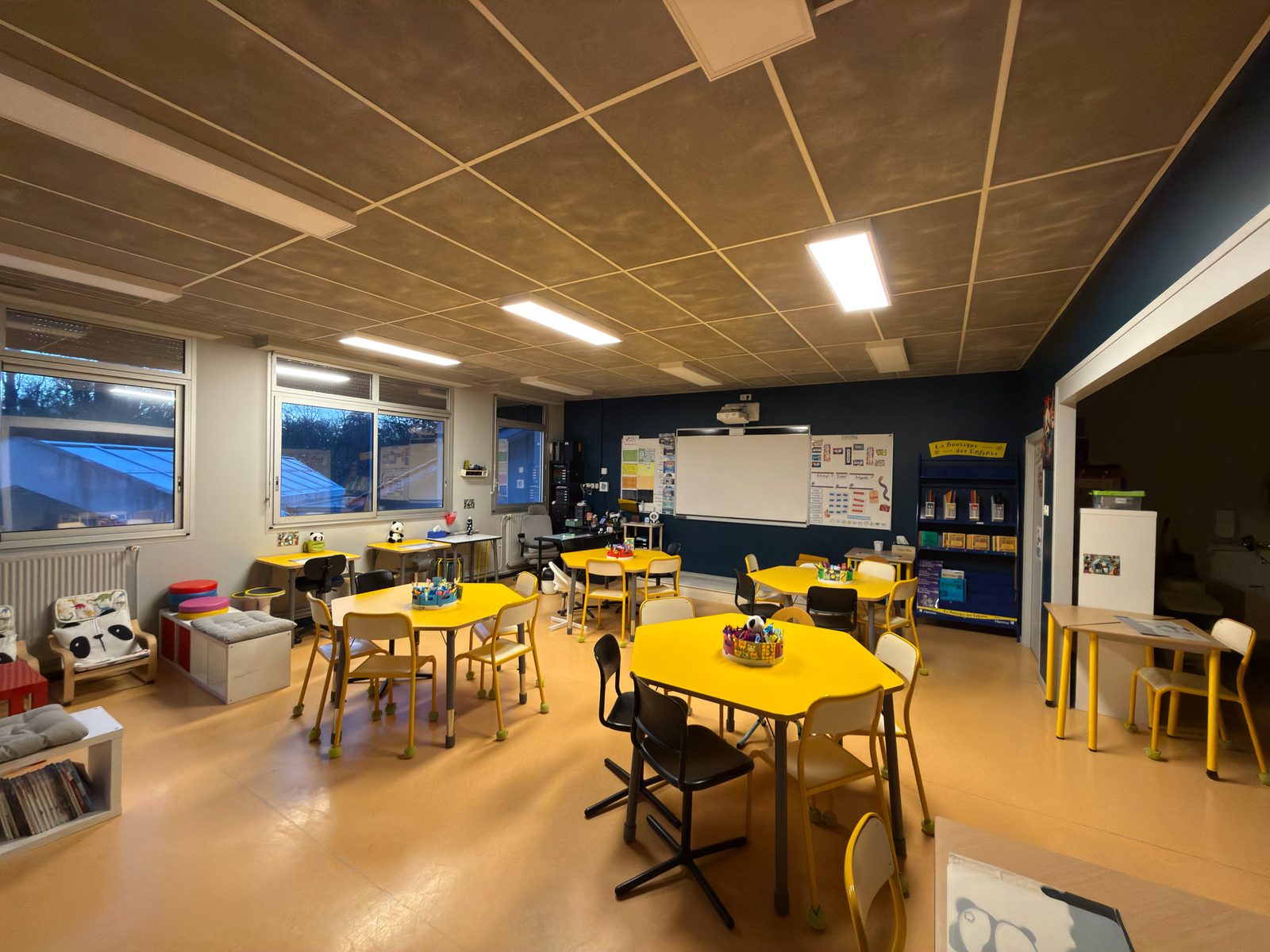 La classe modulable en rentrée 2025 : îlots, coins solos, tables hautes et coussins au sol, sans rangées face au tableau.